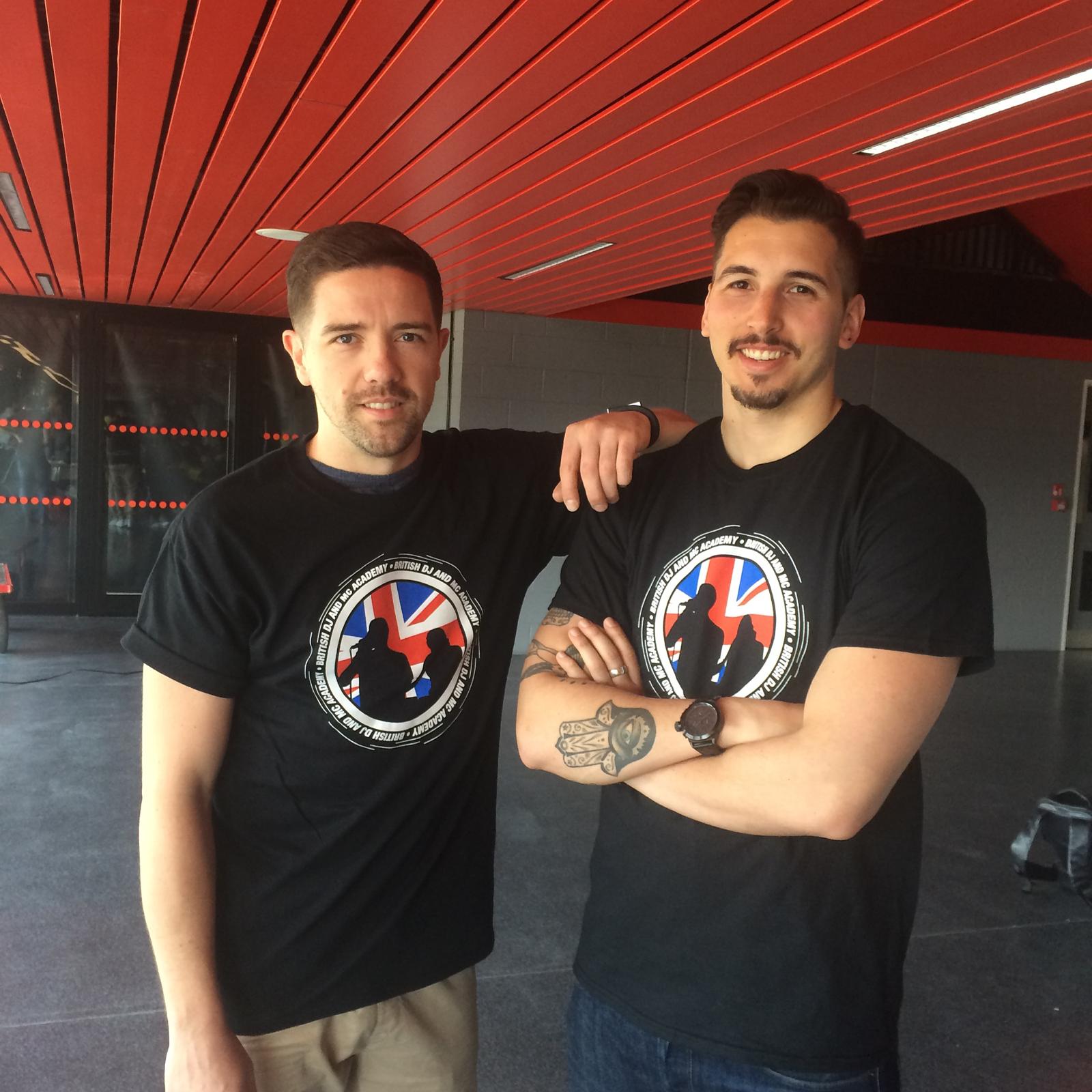 Two members of the DJ & MC team in branded shirts at a stadium venue