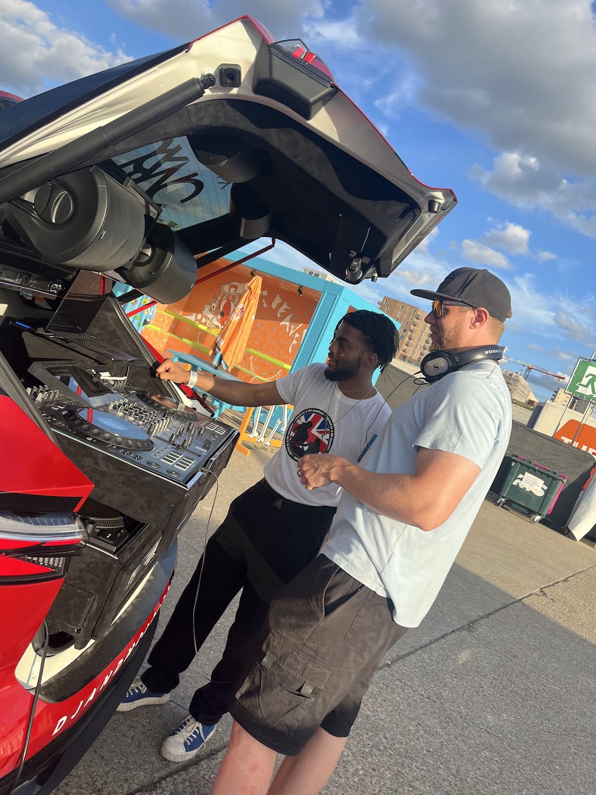 DJ teaching a guest on the decks at the open boot of the DJ car at Beavertown