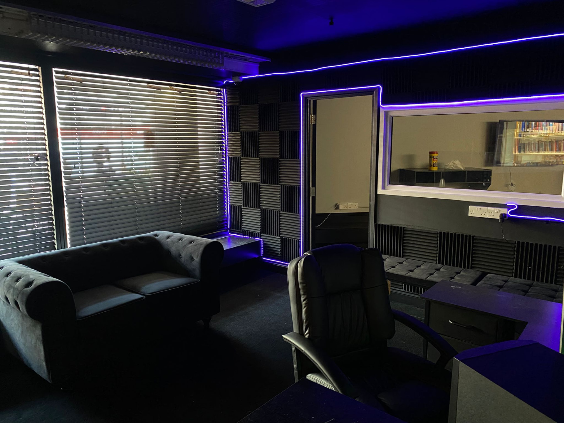 Studio lounge lit in purple with sofa and seating