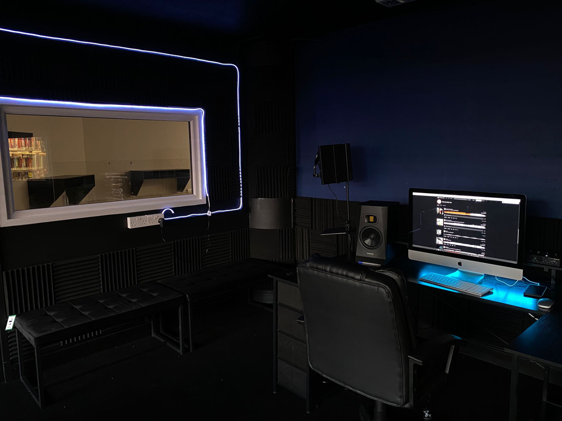 Control room with lit observation window and production desk