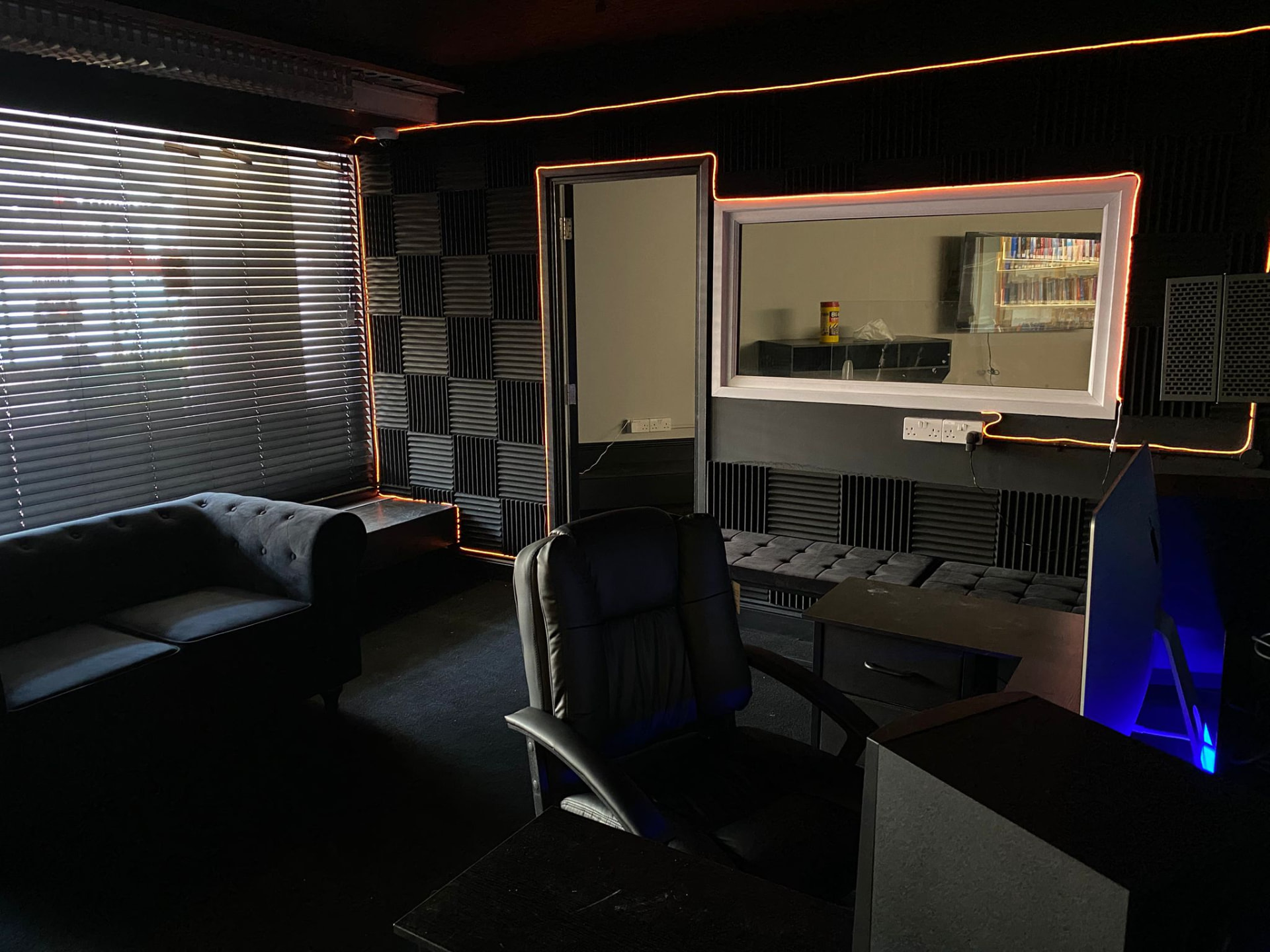 Studio lounge with sofa, acoustic panels and orange LED lighting