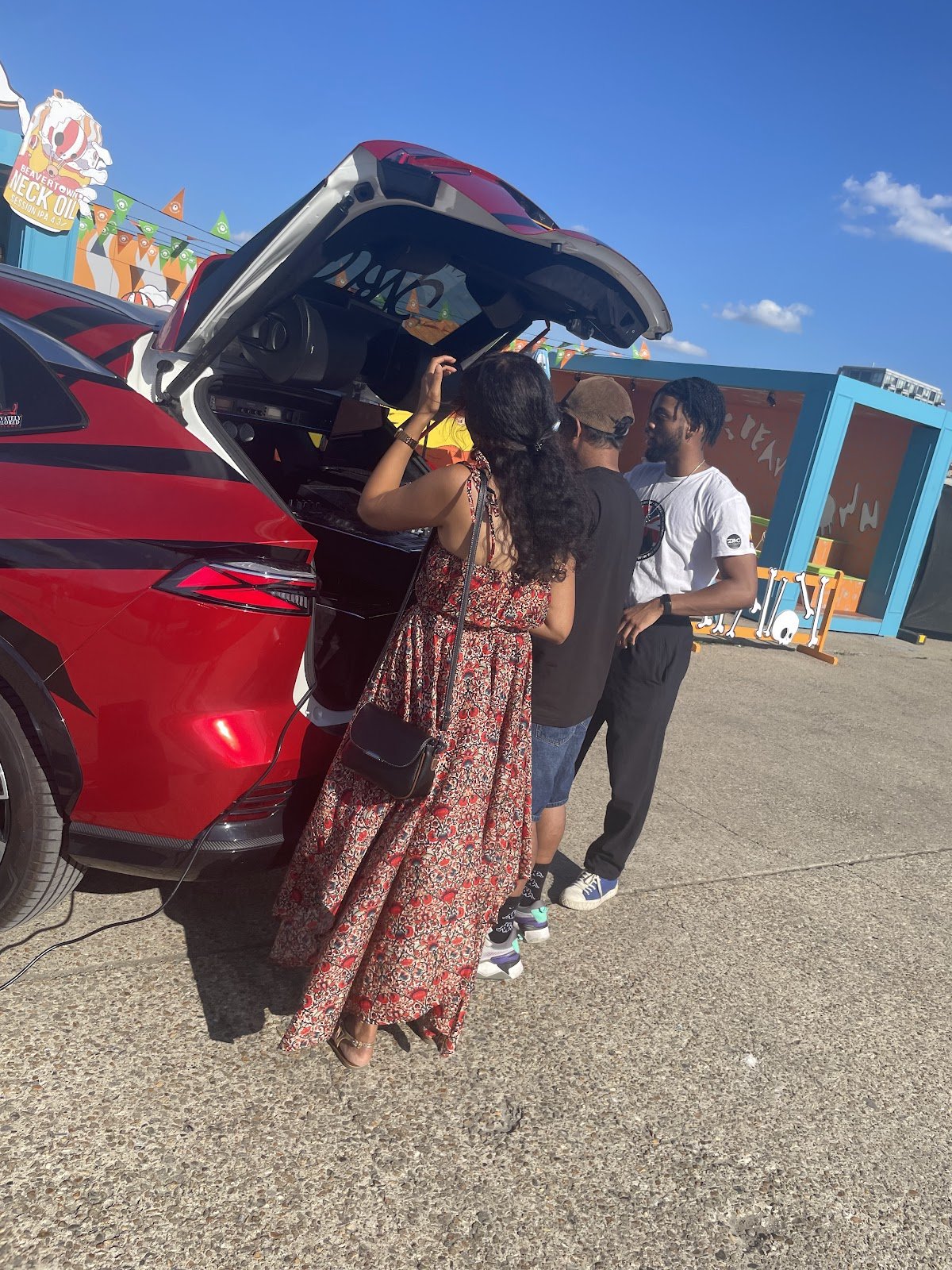Guests gathering at the DJ car's open boot at a Beavertown outdoor event